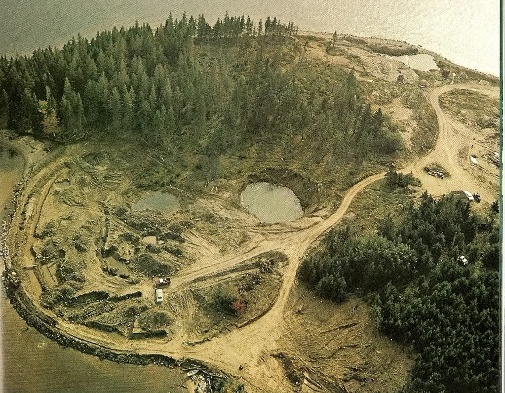 Aerial photograph of the island's east end scarred by craters, water-filled pits and bulldozed tracks.