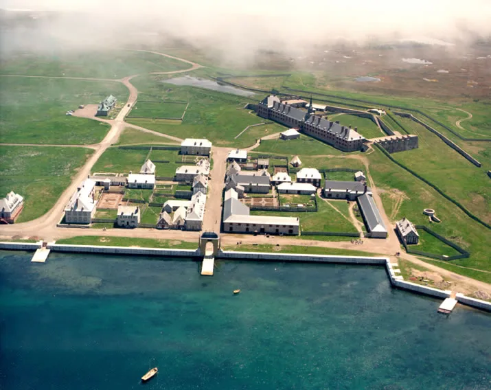 Aerial view of the reconstructed fortress and walled town on a green peninsula beside the sea.