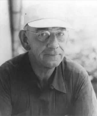 Portrait of an older man in a white cap and wire-rimmed glasses, looking to one side.