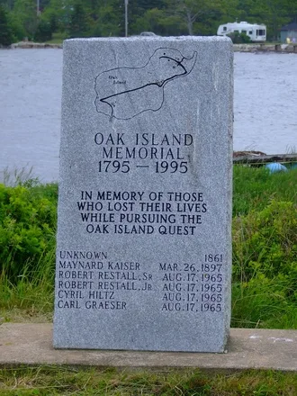 A granite memorial engraved with an outline of the island and the names of six people who died between 1861 and 1965.
