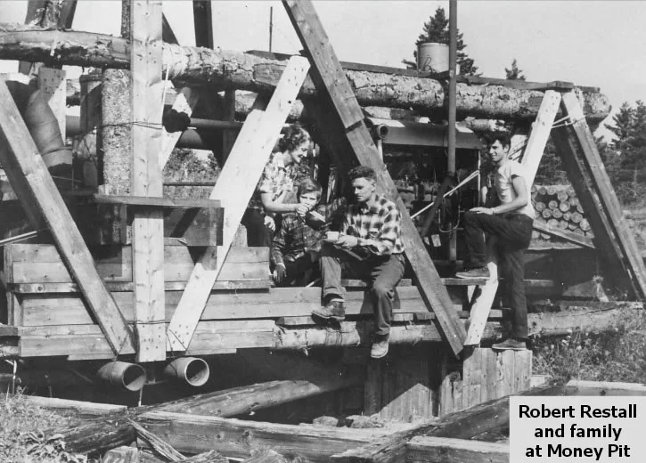 A family seated on a heavy timber platform built over the shaft, with pipes and cribbing visible below.